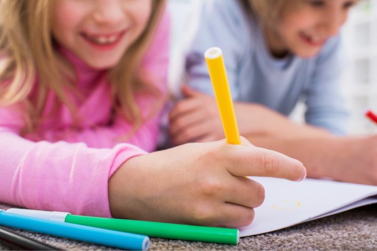 Bambini che disegnano sul foglio con i pennarelli