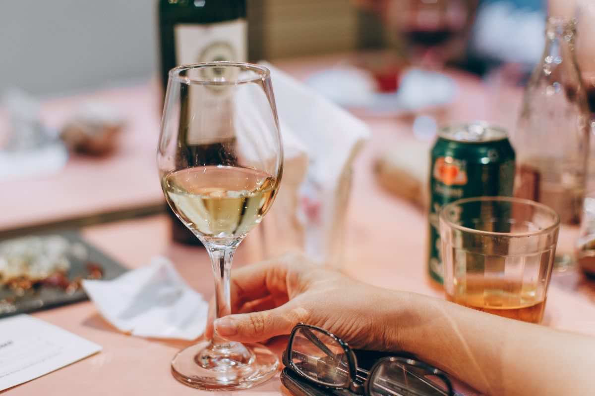 Persona a tavola e calice di vino bianco