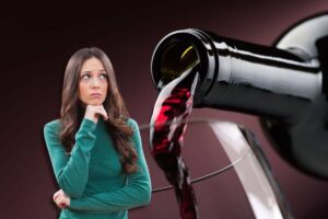 Bottiglia di vino rosso calice e donna in primo piano